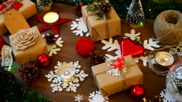 Noel ve yeni yıl arka plan sunar, ışıklar, mumlar ve farklı süslemeler ile. Kraft kağıt kızıl çam ağacı ile hediye. — Stok video