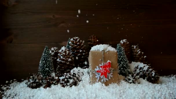 Різдвяний і новорічний фон зі снігом, сосновими шишками, присутній з червоною ялинкою. Повільний рух . — стокове відео