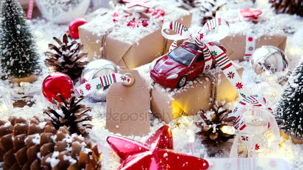 Navidad y Año Nuevo fondo con juguete coche presente con cinta. Bolas, piñas y diferentes decoraciones en la nieve . — Vídeo de stock