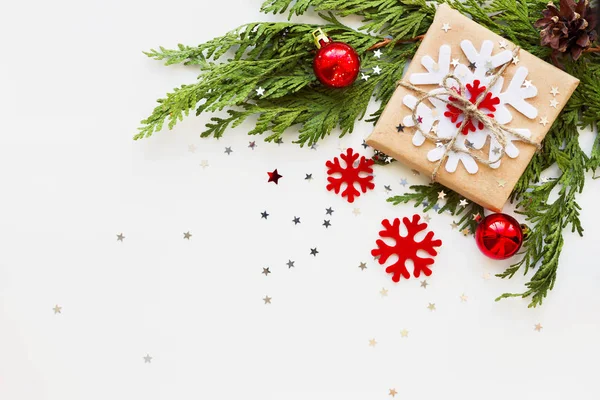 Χριστούγεννα και Πρωτοχρονιά με φόντο με υποκατάστημα τούγιες, διακοσμήσεις και δώρο τυλιγμένο σε χαρτί βιοτεχνίας με νιφάδες χιονιού. Επίπεδη lay, κορυφαία θέα. Θέση για το κείμενο. — Φωτογραφία Αρχείου