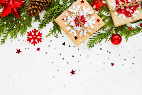 Christmas and New Year background with thuja branch, decorations and presents wrapped in craft paper with snowflakes. Flat lay, top view.