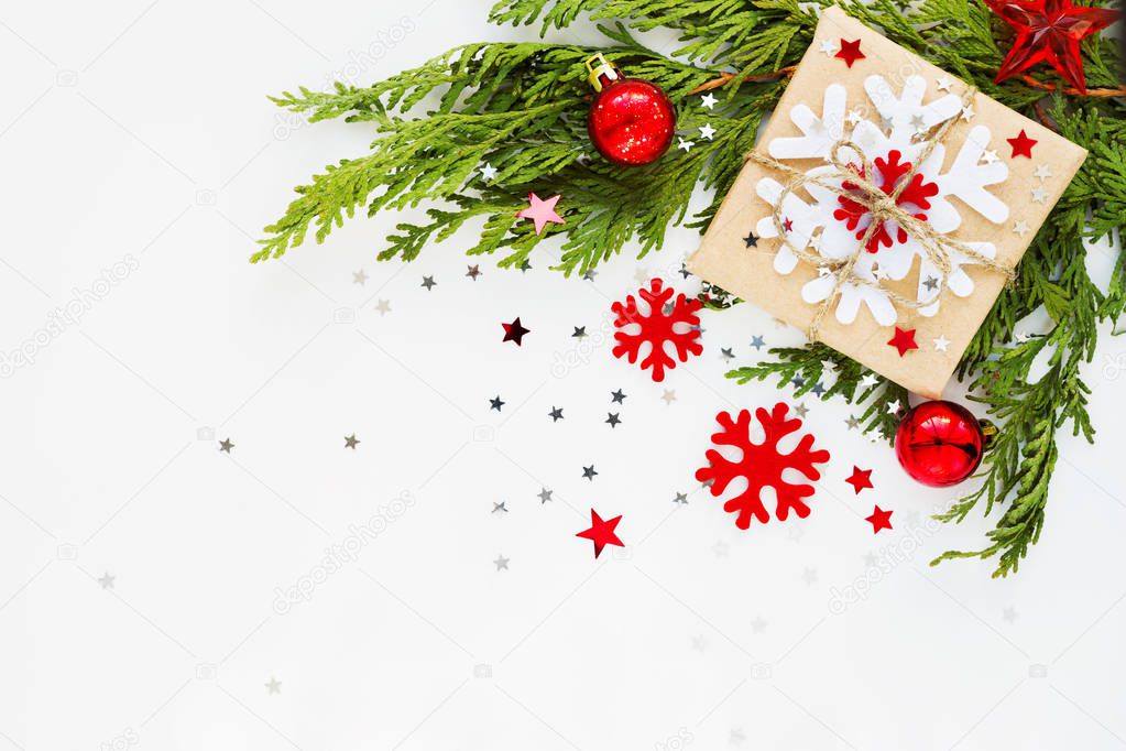 Christmas and New Year background with thuja branch, decorations and present wrapped in craft paper with snowflakes. Flat lay, top view. Place for text.