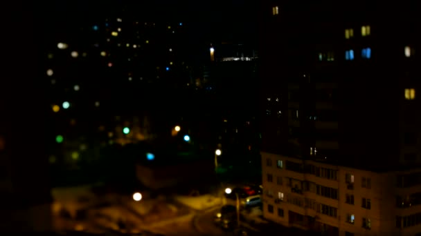 Suddig timelapse klipp av natt gatuliv. Flygfoto av flerbostadshus, parkering bilar och förbipasserande. — Stockvideo