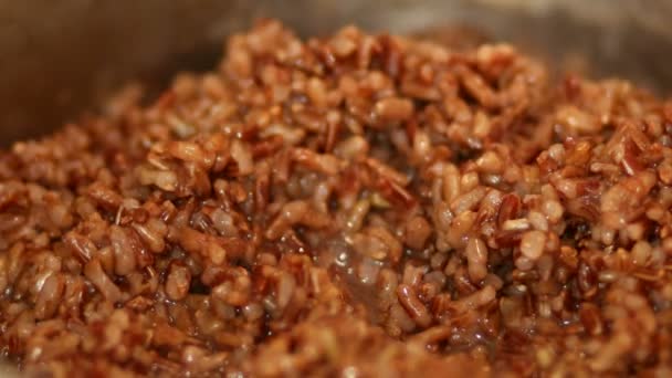 Red rice is boiling in a pot of water. — Stock Video