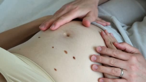 Der nackte Bauch einer schwangeren Frau. kann man sehen, wie sich das Kind im Inneren bewegt. zukünftige Mama und Papa streicheln Bauch. — Stockvideo