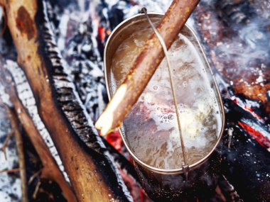 Bir yangın pot pişirme yemek. Ormanda kamp kış.