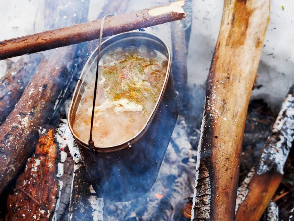 Cooking soup on a fire pot. Winter camping in forest. — Stock Photo, Image