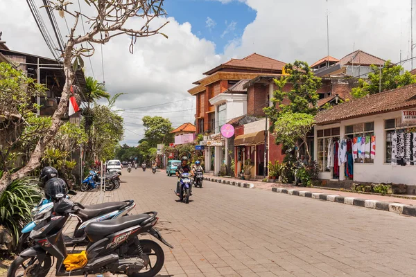 UBUD, INDONESIA - 26 de enero de 2013. La vida callejera en Ubud. La gente conduce motos y coches. Pequeñas tiendas venden souvenirs y tours para turistas . — Foto de Stock