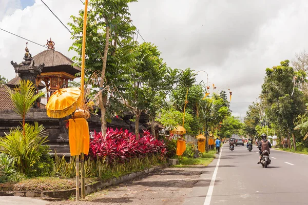 UBUD, INDONESIA - 26 de enero de 2013. Decoración religiosa cerca de casas en la calle. Tráfico por carretera en un día soleado . — Foto de Stock