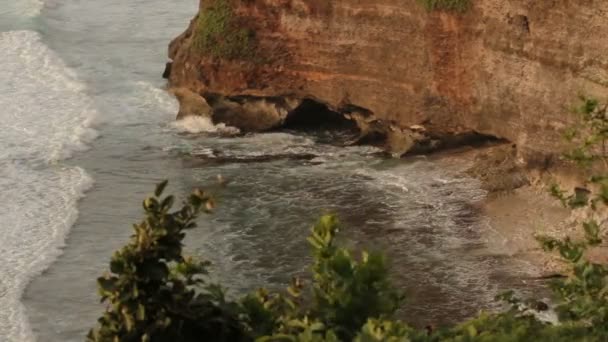 Surfa på en stenig strand nära Pura Luhur Uluwatu. Bali island Indonesien. — Stockvideo