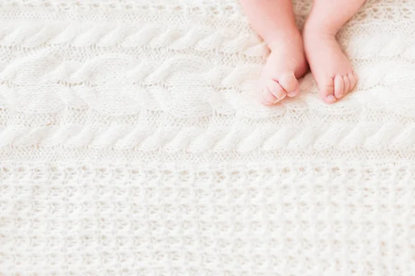 Baby's feet on white knitted background. Little child's bare feet. Cozy morning bedtime at home. Place for text. — Stock Photo, Image