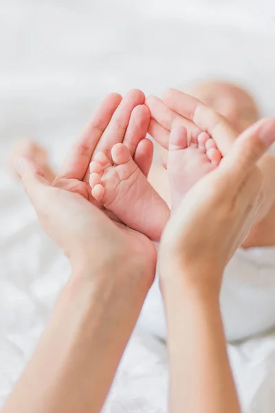 Mamma håller nyfödd bebis bara fötter. Små fötter i kvinnans hand. Mysig morgon hemma. — Stockfoto