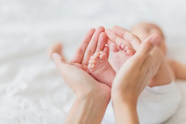 Mamma håller nyfödd bebis bara fötter. Små fötter i kvinnans hand. Mysig morgon hemma. — Stockfoto