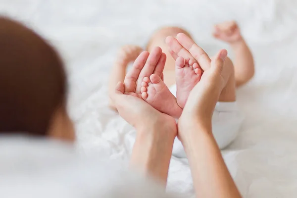 Mamma håller nyfödd bebis bara fötter. Små fötter i kvinnans hand. Mysig morgon hemma. — Stockfoto