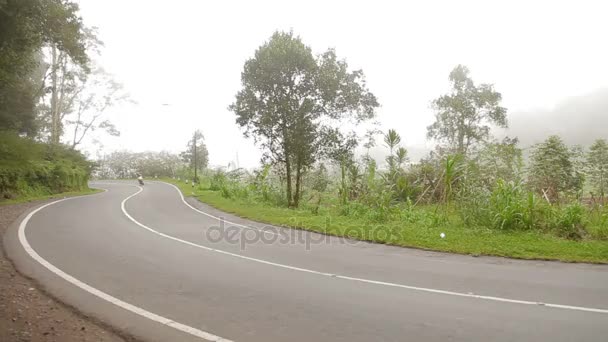 KINTAMANI, INDONESIA - 26 gennaio 2013. Nebbia pesante sulla strada brutto tempo per la guida di moto. Strada attraverso la nebbiosa foresta sempreverde giungla. Stagione delle piogge invernali. Indonesia . — Video Stock