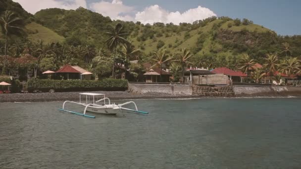 BALI, INDONESIA - 29 de enero de 2013. Catamarán flotando en las olas. Playa con bungalows para turistas en la orilla . — Vídeos de Stock