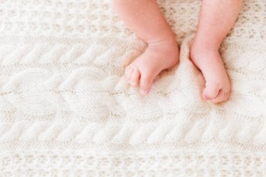 Bebeğin ayakları üzerinde beyaz arka plan ördü. Küçük çocuğun çıplak ayak. Sabah yatmadan evde rahat. Metin için yer.