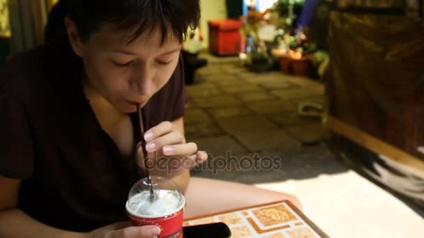 Bangkok, Thaiföld - október 20., 2013. Nő ital zöld tea tejszínhabbal. Nő szereti a hideg italok. — Stock videók