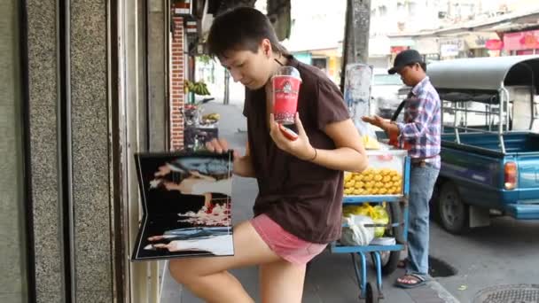 Bangkok, Tajlandia - Październik 20, 2013. Kobieta piciem zielonej herbaty z bitą śmietaną i zaglądać książki Fotografia ślubna. PhotoStudio showcase. — Wideo stockowe