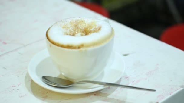 La taza del capuchino del café con el azúcar sobre la espuma. Bebida caliente dulce en taza blanca . — Vídeo de stock