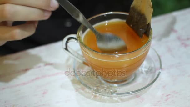 Vrouw roert vruchten thee met een lepel. Theezakje in transparante beker. Straat café in Bangkok, Thailand. — Stockvideo