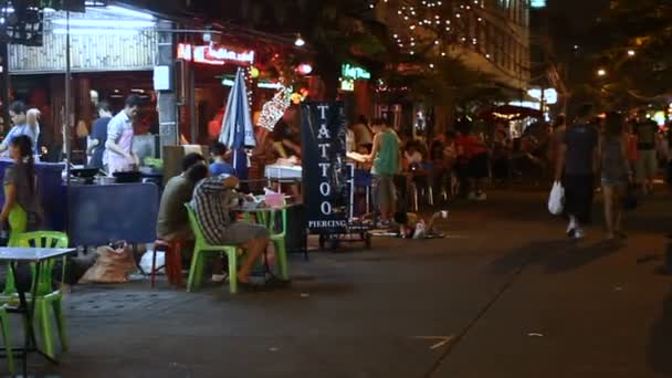 Bangkok, Tajlandia - Październik 22, 2012. Życie nocne na Khao San road. Mieszkańców i turystów siedzieć w Kawiarnie i restauracje, ozdobiony kolorowe lampy i latarnie, chodzić po ulicy. — Wideo stockowe