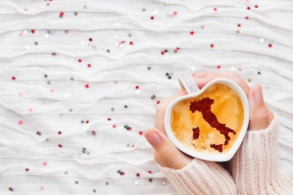 Frau hält eine Tasse heißen Kaffee mit Zimt Silhouette von Italien. Winterreiselust und Valentinstag Stoff Hintergrund mit glitzerndem Silber und rotem Konfetti. — Stockfoto