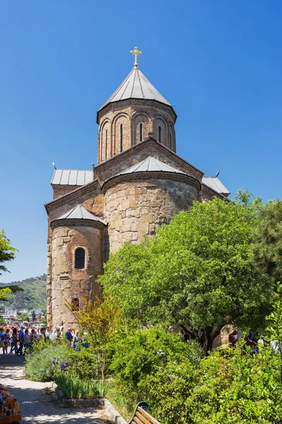 TBILISI, GEORGIA - 1 de mayo de 2017. Turistas cerca de la Iglesia Metekhi de la Dormición de la virgen. Monumento famoso en Tiflis, Georgia . — Foto de Stock