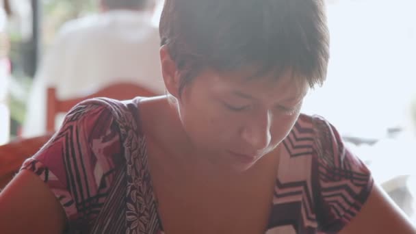 女人坐在咖啡馆和滑动屏幕的平板电脑。柬埔寨. — 图库视频影像