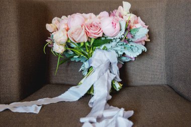 Düğün buketi sandalyede. Gelinin geleneksel sembolik aksesuar. Peonies ve güller çiçek kompozisyonu.
