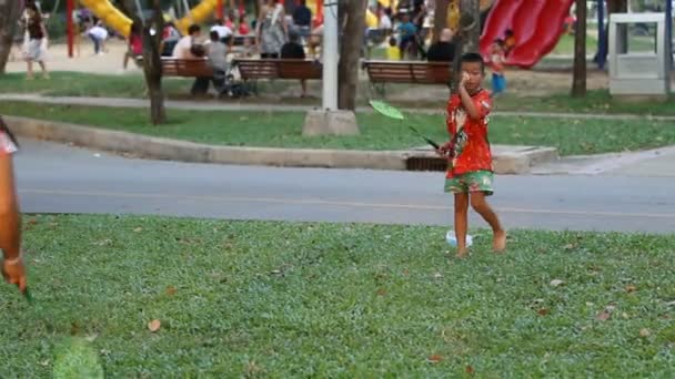 Bangkok, Thailand - 22 oktober 2012. Kvällsaktivitet i Lumpini park. Människor joggar, spelar spel, promenader. Liten pojke plaing badminton med hans mor. — Stockvideo