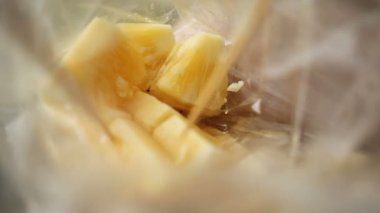 Taze ananas dilimleri plastik torba. Ananas parçası üzerinde tahta bir sopa yapışmasını kadın. Meyve yeme geleneksel Asya yöntemi. Tayland.