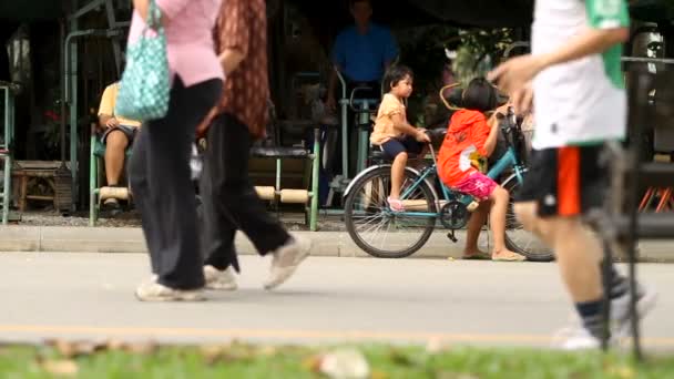 Bangkok, Thajsko - 24. října 2012. Děti jezdit na kole poblíž venku provizorní tělocvična. Lumpini park. — Stock video