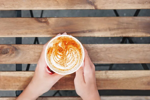 Vrouw met een papieren kopje koffie. Koffie te gaan. Lekkere warme drank op houten tafel in zonnige dag. Buiten de maaltijd. Plat lag, top uitzicht. — Stockfoto