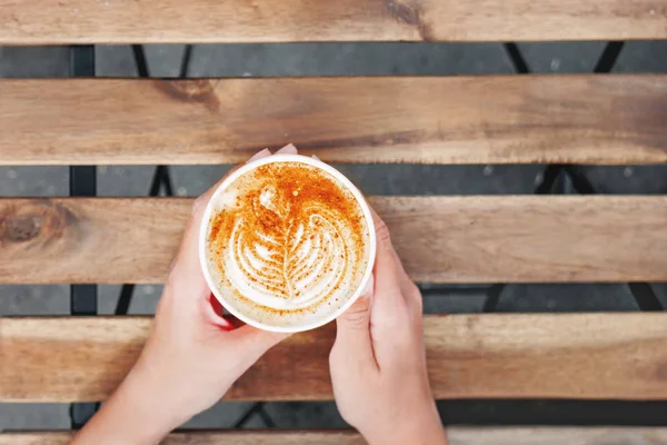 Frau hält eine Papptasse mit Kaffee. Coffee to go. Leckeres Heißgetränk auf Holztisch an sonnigen Tagen. Mahlzeit im Freien. flache Lage, Draufsicht. — Stockfoto