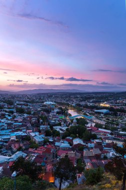 Tbilisi, Georgia ülkeden Narikala kale başkenti gün batımı manzarası. Ünlü simge - Cumhurbaşkanlığı yönetim, aydınlatma ile barış Köprüsü.
