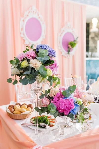 Set da tavola per banchetto di nozze con composizione floreale di rose e ortensie. Decorazione floreale in vaso alto . — Foto Stock