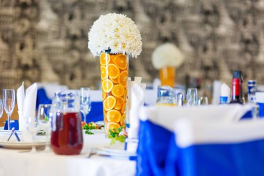 Tablo için düğün Ziyafet çatal ile ayarla. Salatalar, mezeler ve gözlük şarap ile. Dekorasyon öğeleri - portakal dilimleri ve beyaz papatya çiçek vazolar.