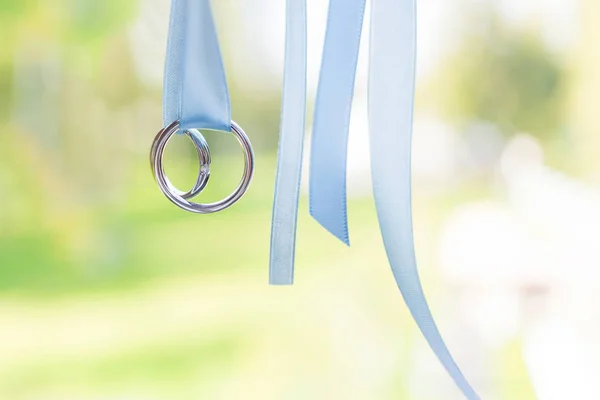 stock image Pair of golden wedding rings with diamond on light blue ribbons. Wedding details, symbol of love and marriage.