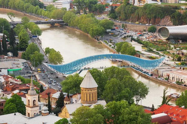 Vista aérea panorámica del hito moderno Puente de la Paz sobre el río Kura. Tiflis, Georgia . — Foto de Stock