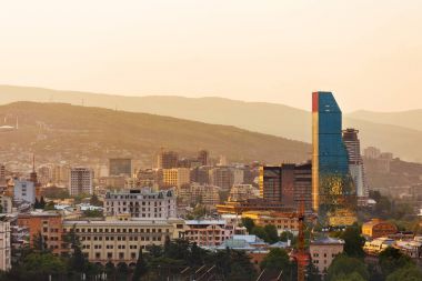 Tbilisi, Georgia ülkeden Narikala kale başkenti günbatımı panorama görünümünü. Modern mimari Simgesel Yapı - gökdelen Biltmore Hotel.