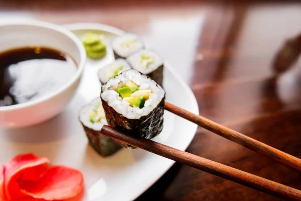 Rollos en algas nori con aguacate, jengibre en escabeche y salsa de soja. Cocina asiática, plato tradicional - sushi . — Foto de Stock