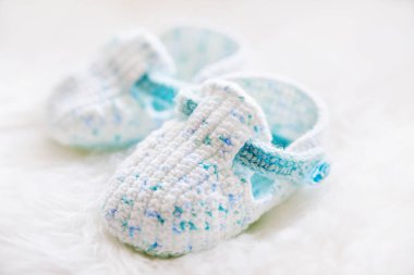 Küçük bebek ayakkabıları. Handknitted ilk ayakkabı erkek ya da kız için. Kabarık beyaz zemin üzerine el yapımı patik tığ işi.