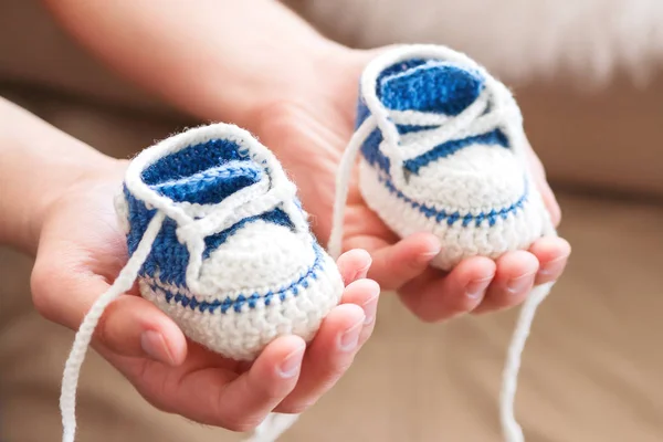 Little baby shoes. Handknitted first sneakers for boy or girl. Crochet handmade bootees in daddy's hands. Newly father presents knitted shoes. — Stock Photo, Image