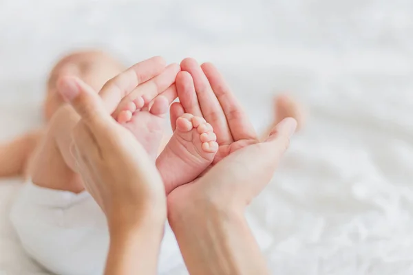 Mamma håller nyfödd bebis bara fötter. Små fötter i kvinnans hand. Mysig morgon hemma. — Stockfoto