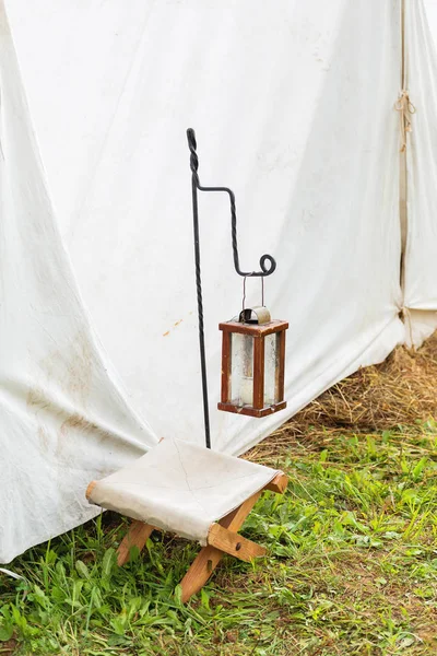 Linterna antigua con vela y silla de campamento en la entrada de la tienda. Reconstrucción histórica del siglo XIX . — Foto de Stock