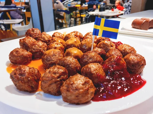 Frische leckere Frikadellen mit Preiselbeersoße auf weißem Teller mit schwedischer Flagge. — Stockfoto