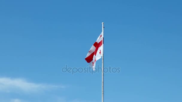 Vlag van Georgia land wuiven in de wind tegen heldere blauwe hemel in zonnige dag. — Stockvideo