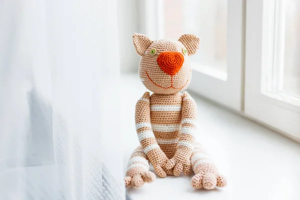 Handmade knitted toy cat. Beige paws with white stripes.