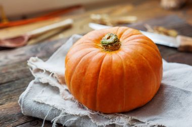 Taze turuncu ahşap masa üzerinde kabak. Saf peçete ve arka plan üzerinde rustik çatal bıçak takımı.